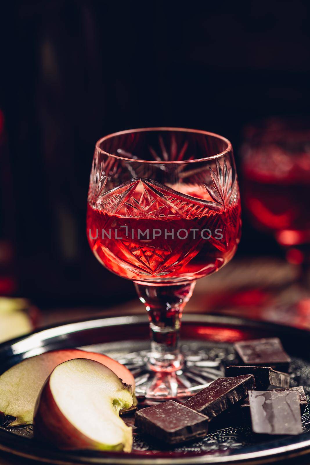 Homemade red currant nalivka and chocolate with sliced apple on metal tray