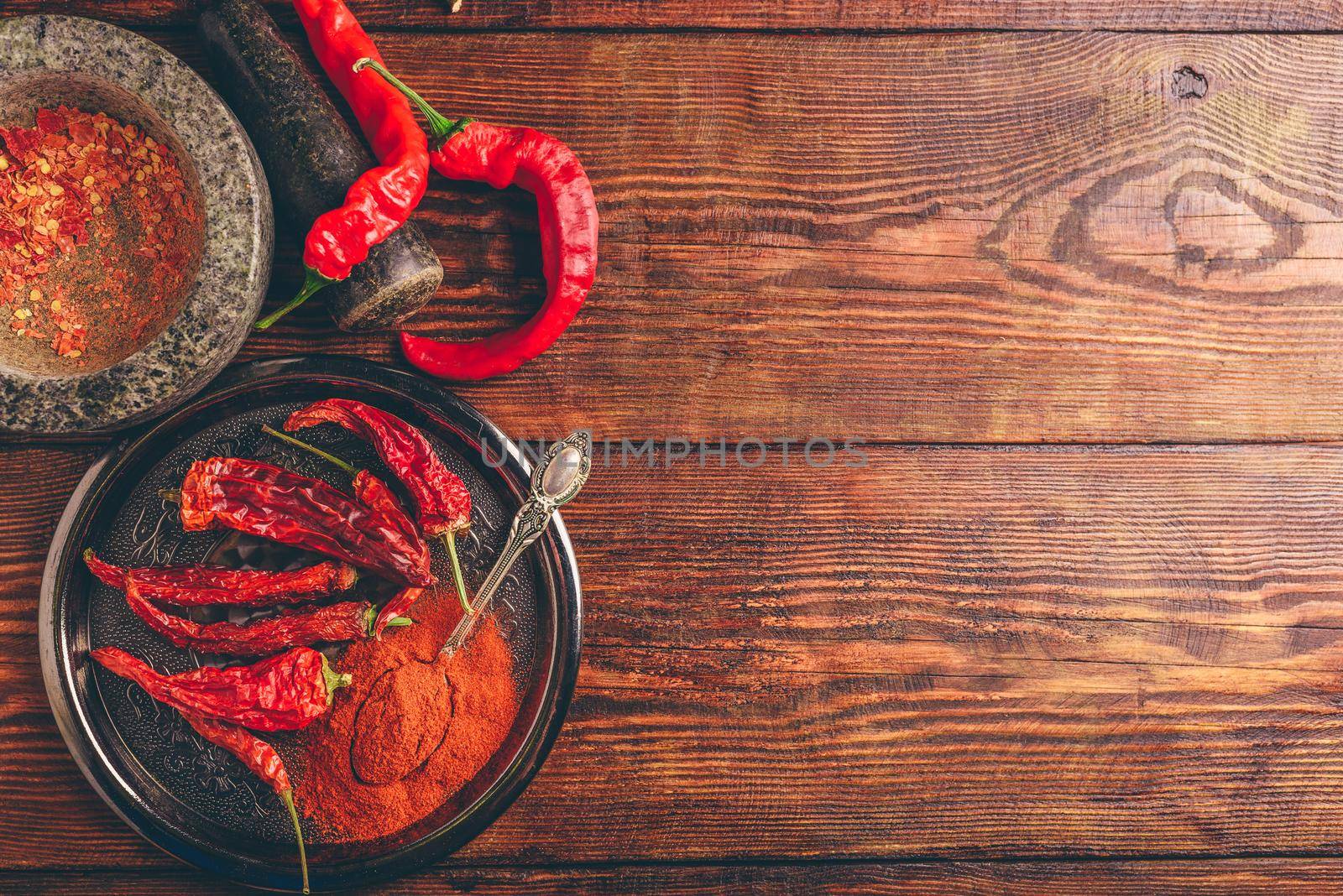 Fresh, dried and ground red chili peppers over wooden surface. Copy space