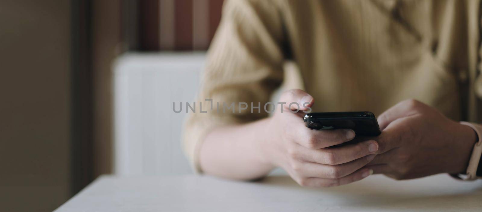 Mockup image of a woman holding mobile phone with blank black screen in cafe.