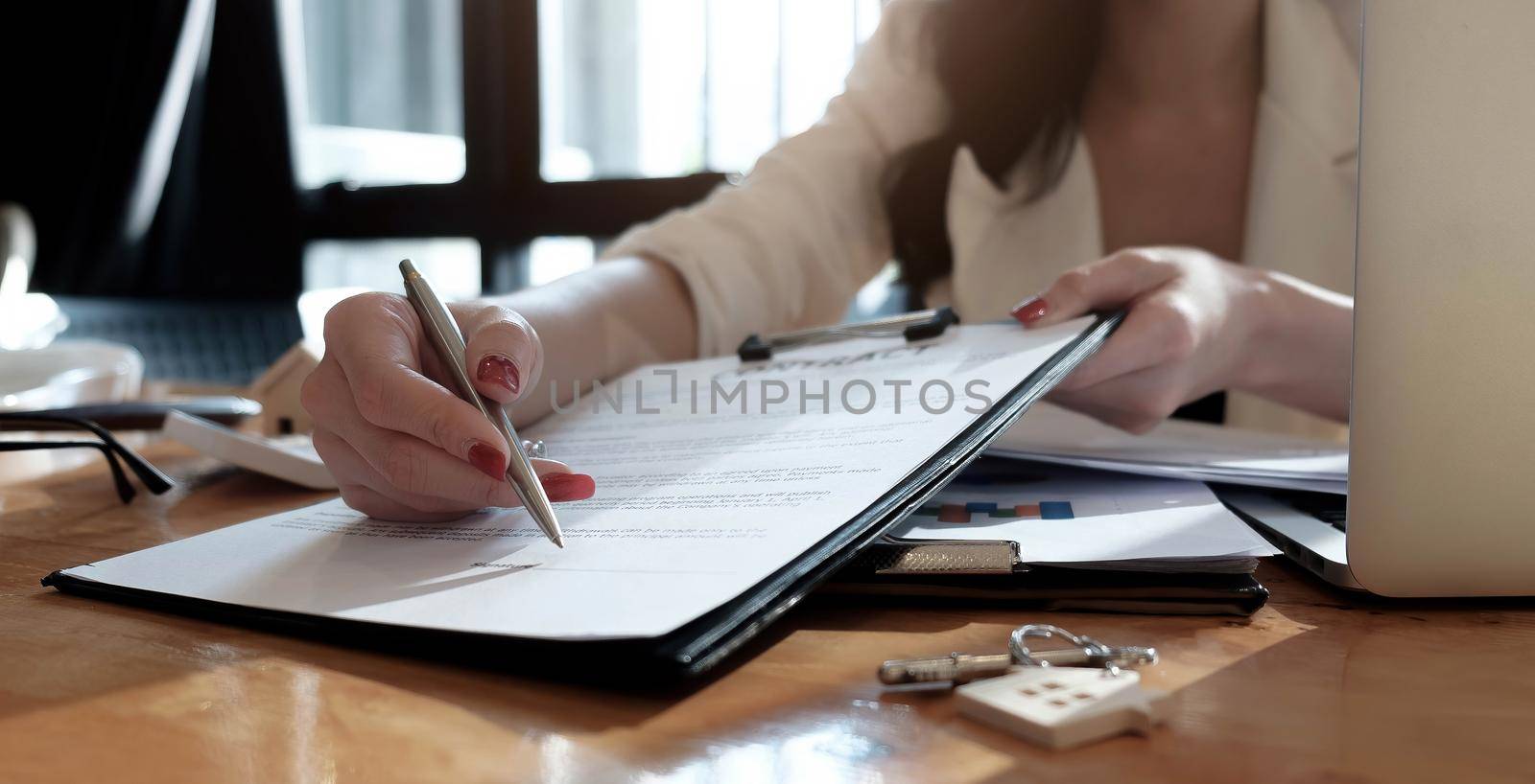 real estate agent assisting client to sign contract paper at desk with house model.