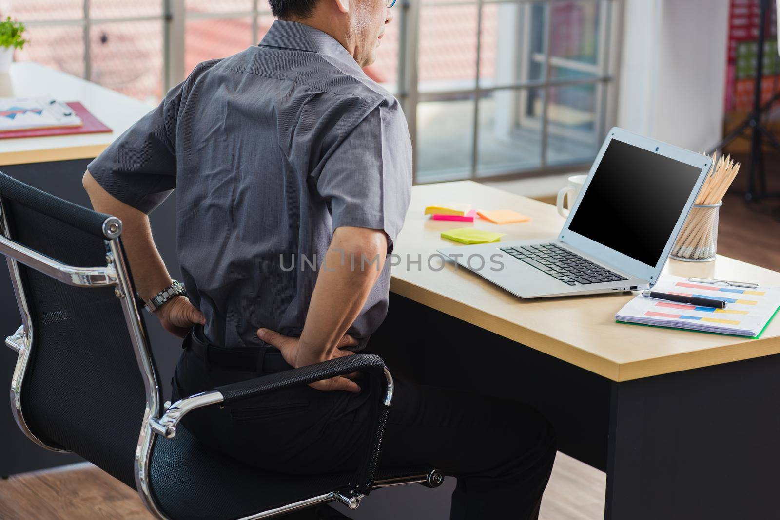 Asian hard senior businessman working with laptop computer has a problem with back pain. Old man feeling pain after sitting at desk long time, Healthcare and medicine office syndrome concept