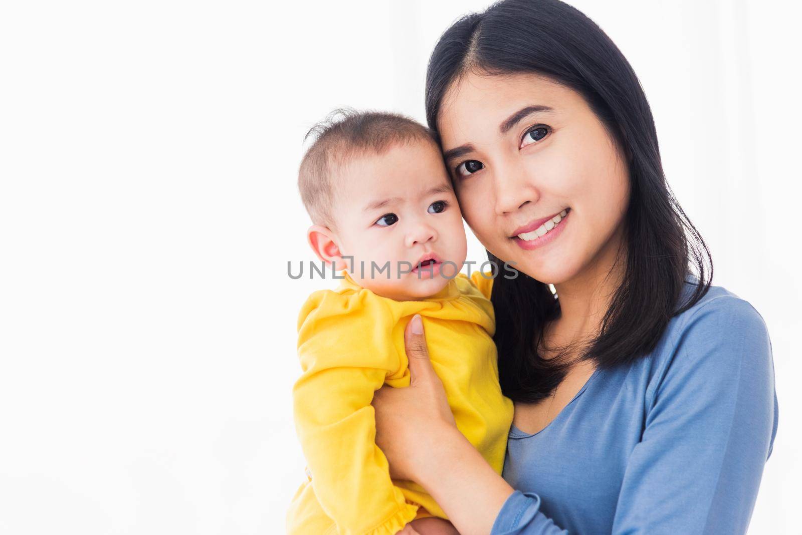 Portrait of beautiful young Asian mother holding his newborn little baby in her arms at home, Parent mom hugging her newborn child, happy family