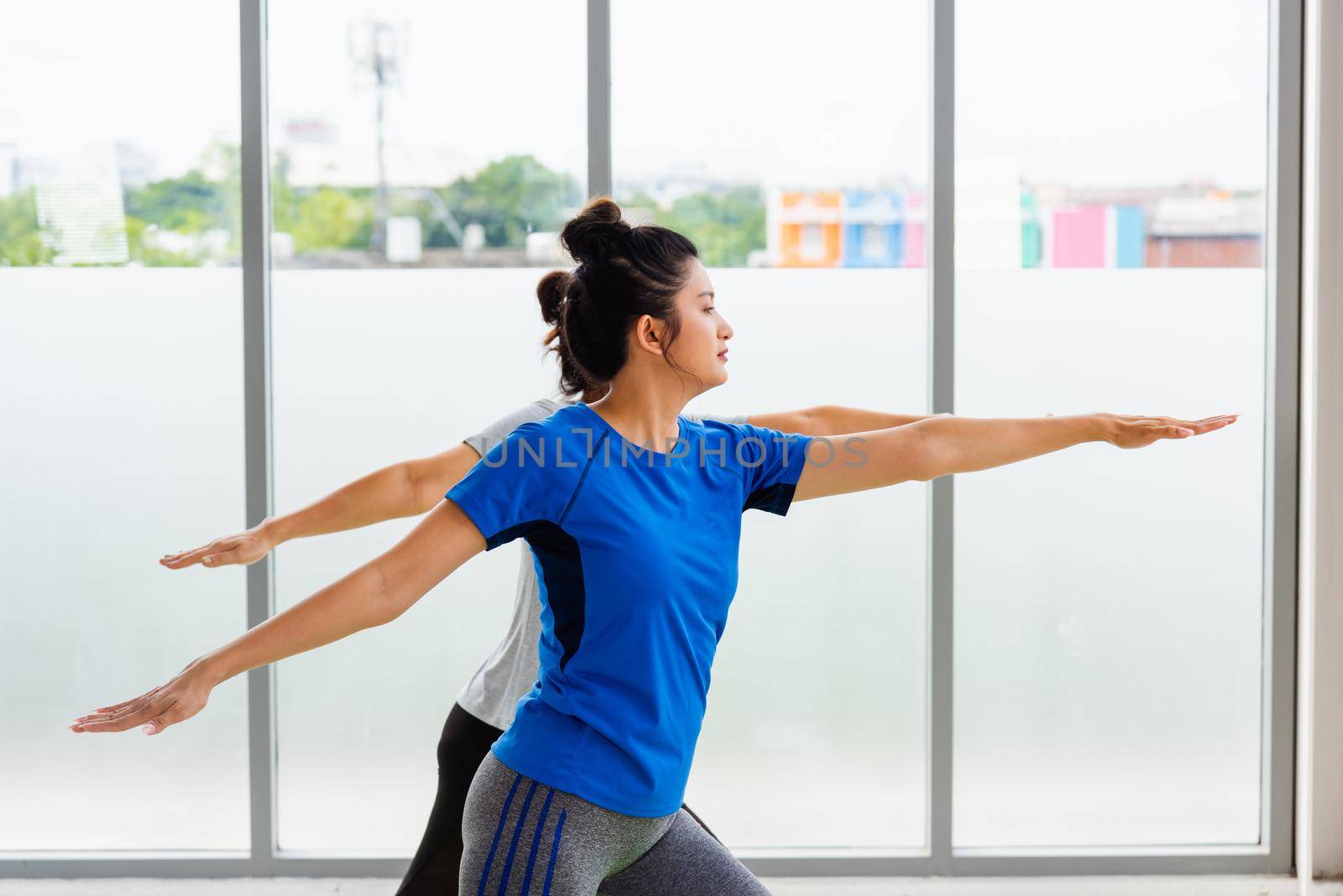 Two Asian women sporty attractive people practicing yoga lesson together, working out at the fitness GYM, Young and senior female exercising do yoga in yoga classes, sport healthy lifestyle