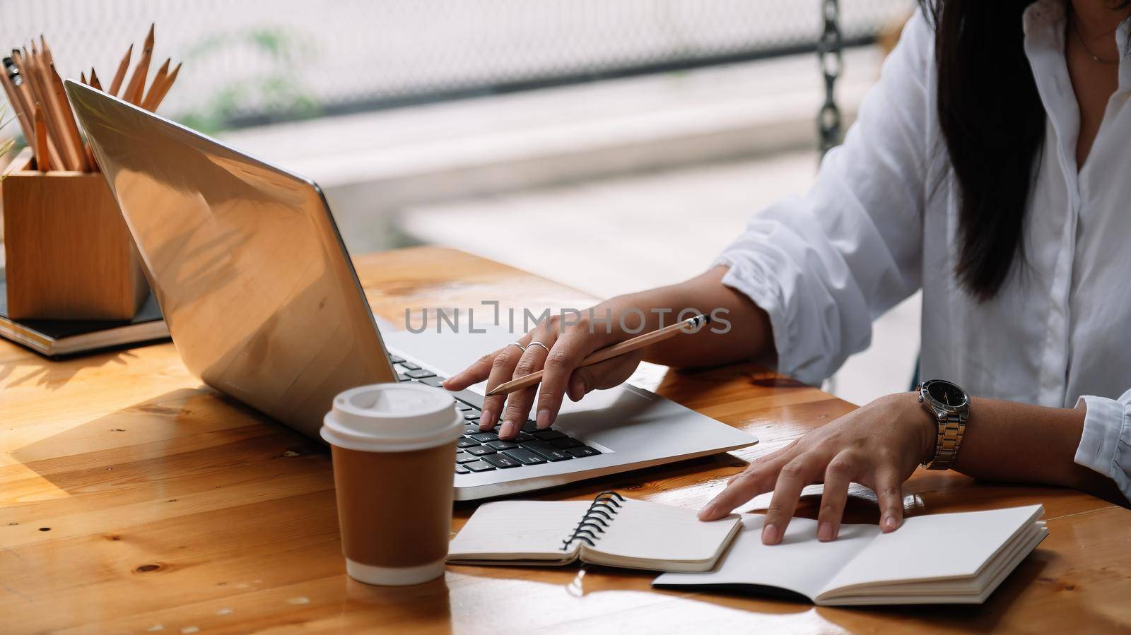 Cropped photo of woman writing making list taking notes in notepad working or learning on laptop indoors- educational course or training, seminar, education online concept