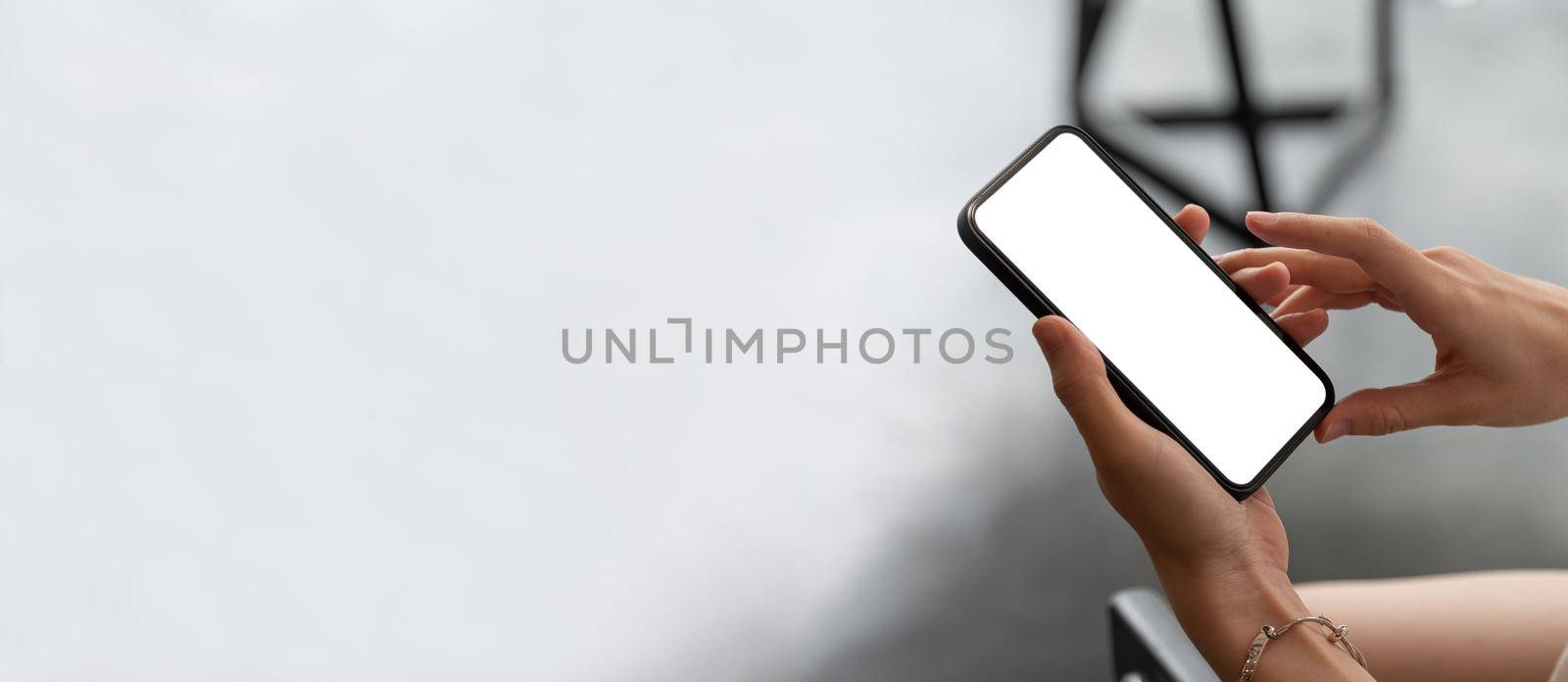 Mock up phone in woman hand showing white screen on top view.