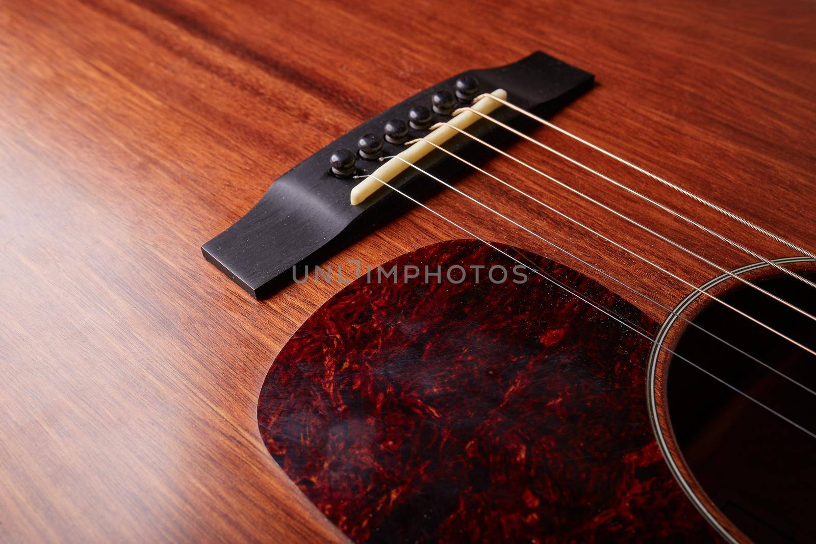 The bridge and strings of and acoustic guitar. Close up. Selective focus