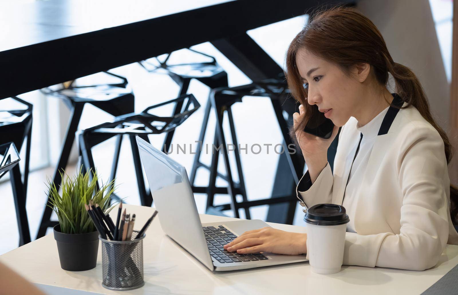 Photo of asian business woman working as content manager arranging with her customers by smart phone.