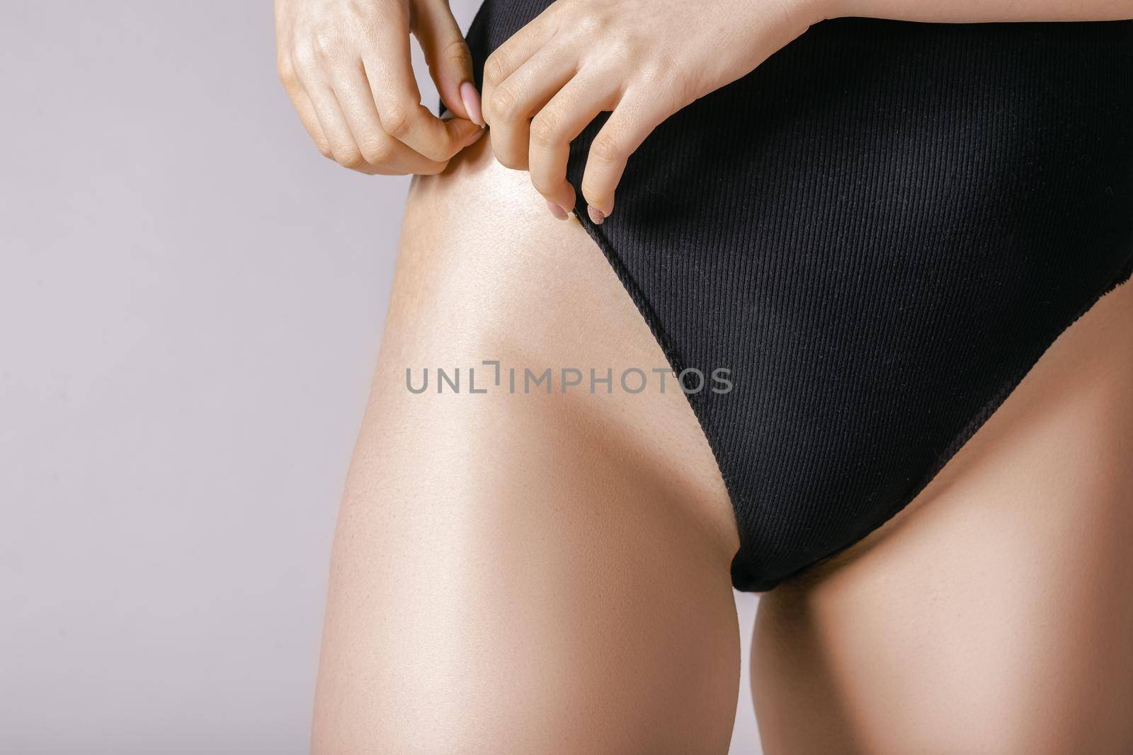 A young woman straightens her panties with her hands. Close-up