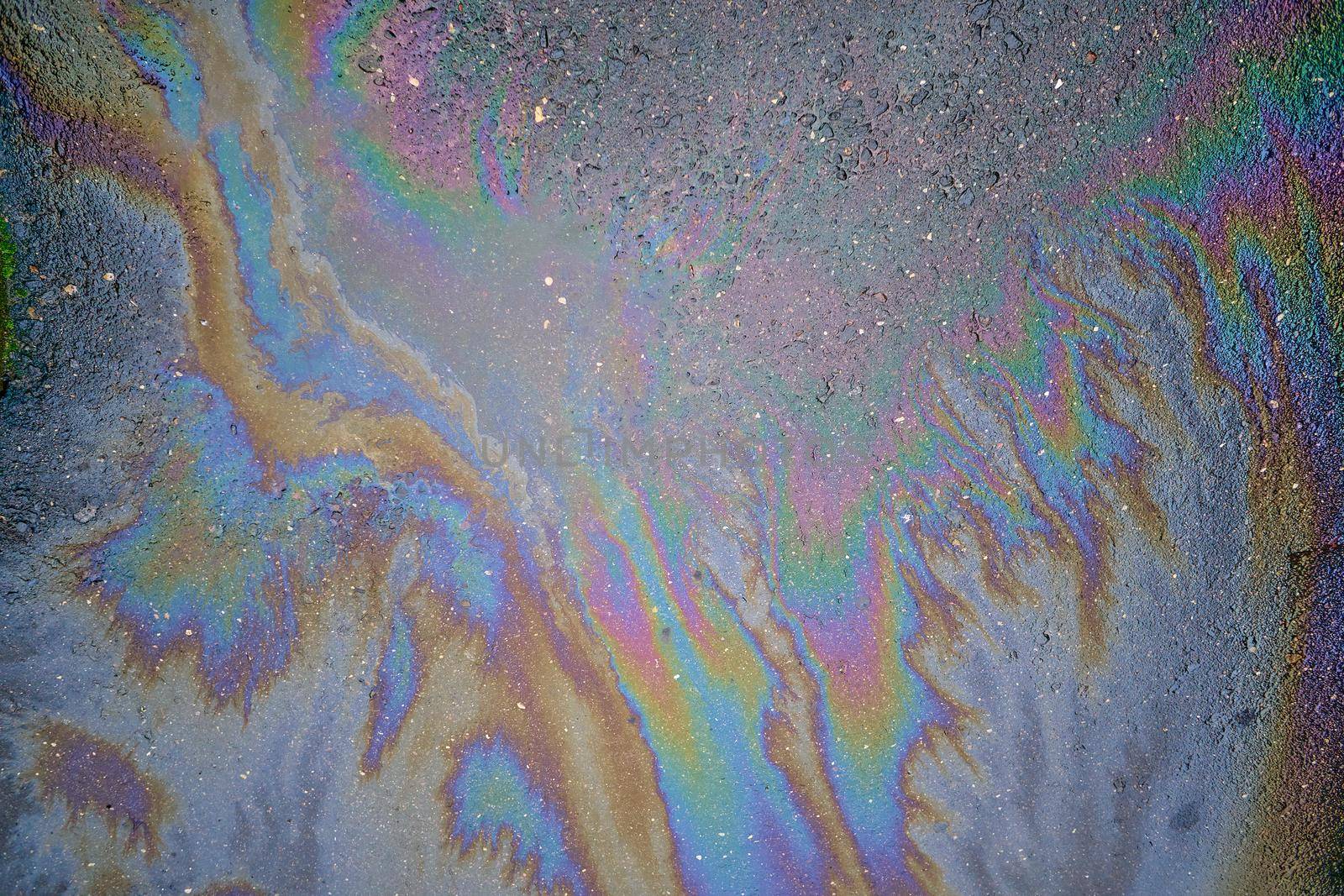 Colored oil stains in the car park, the color of the gasoline stain on the pavement road as a texture or background.Abstract rainbow effect background