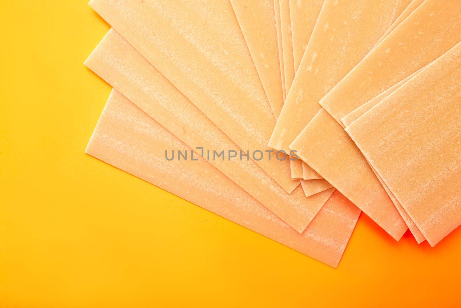Raw lasagna pasta on white yellow-orange background