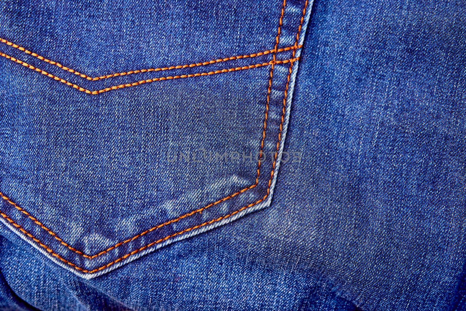 Blue denim jeans background pocket with seam and orange thread stitches close-up. Casual urban classic fashion