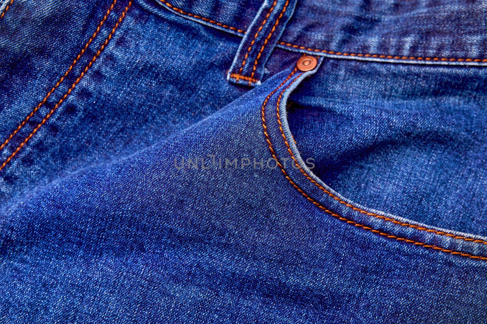 Blue denim jeans background pocket with seam and orange thread stitches. Casual urban classic fashion