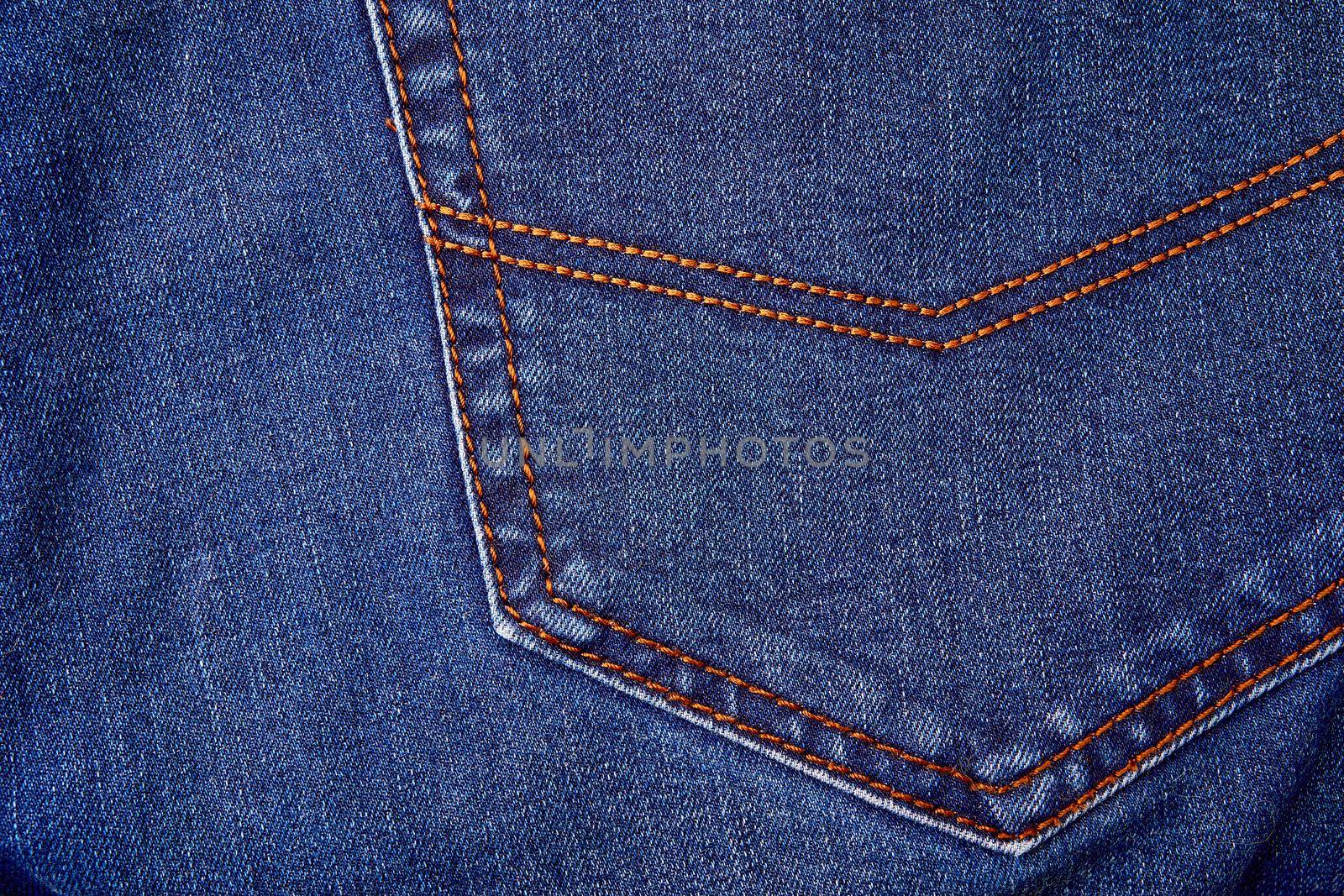 Blue denim jeans background pocket with seam and orange thread stitches. Casual urban classic fashion