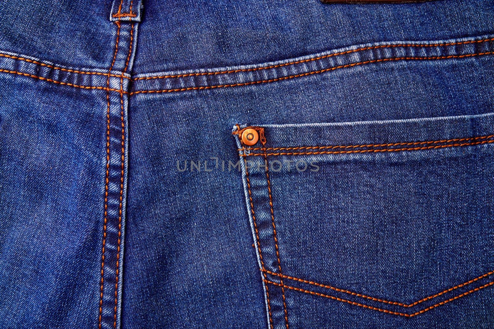 Blue denim jeans background pocket with seam and orange thread stitches. Casual urban classic fashion