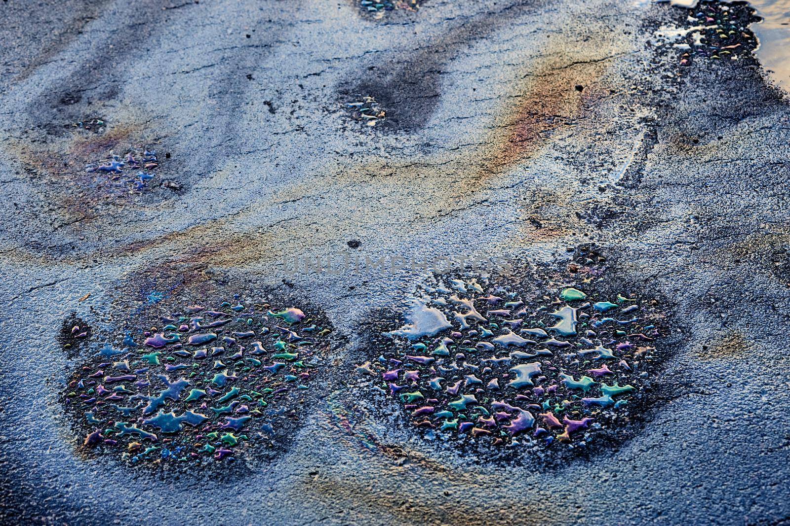 Oil stain on wet asphalt caused by a leak under a car or truck.Environmental petrol oil pollution.