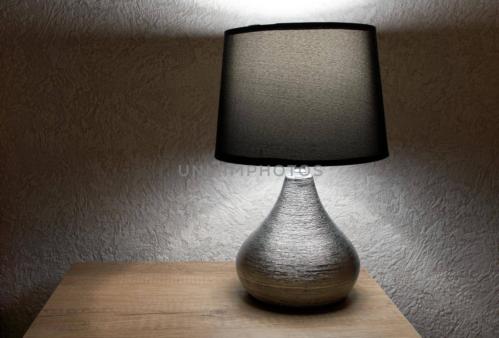 tylish lamp on table against wall, space for text.