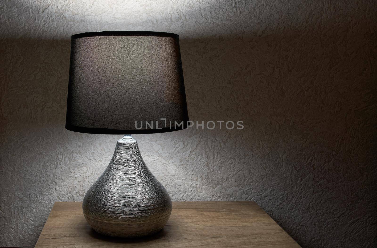 tylish lamp on table against wall, space for text.