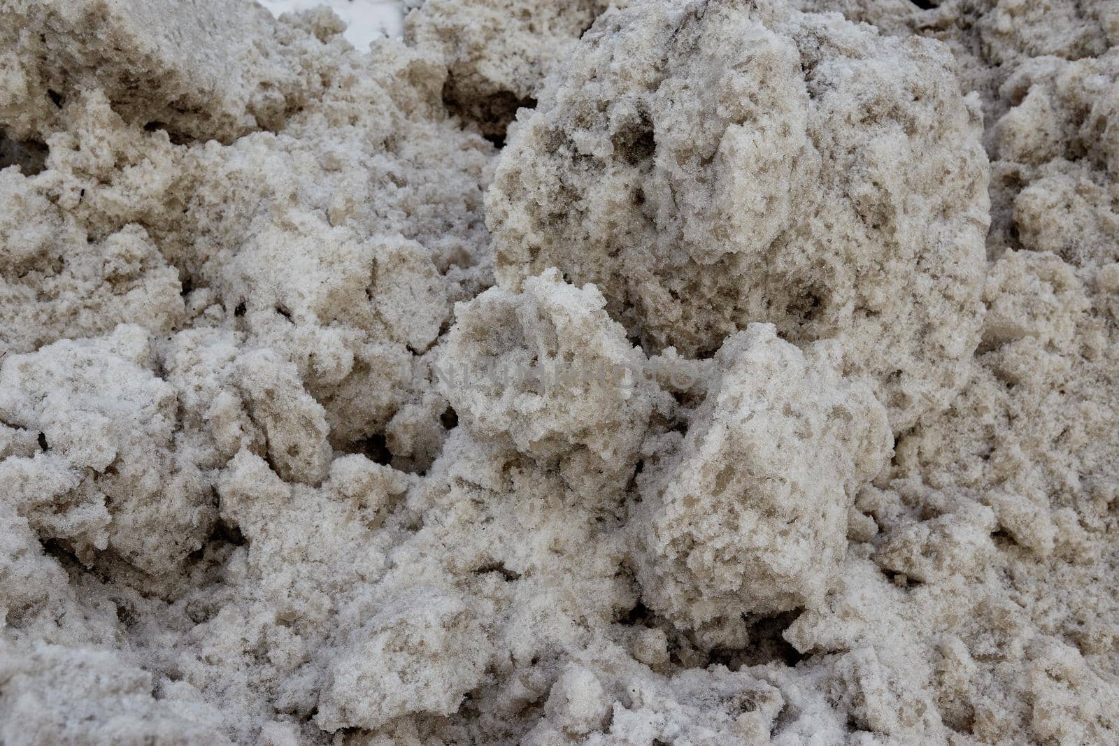 Texture of caked thawed dirty snow. Dirty snow. The concept of snow removal.