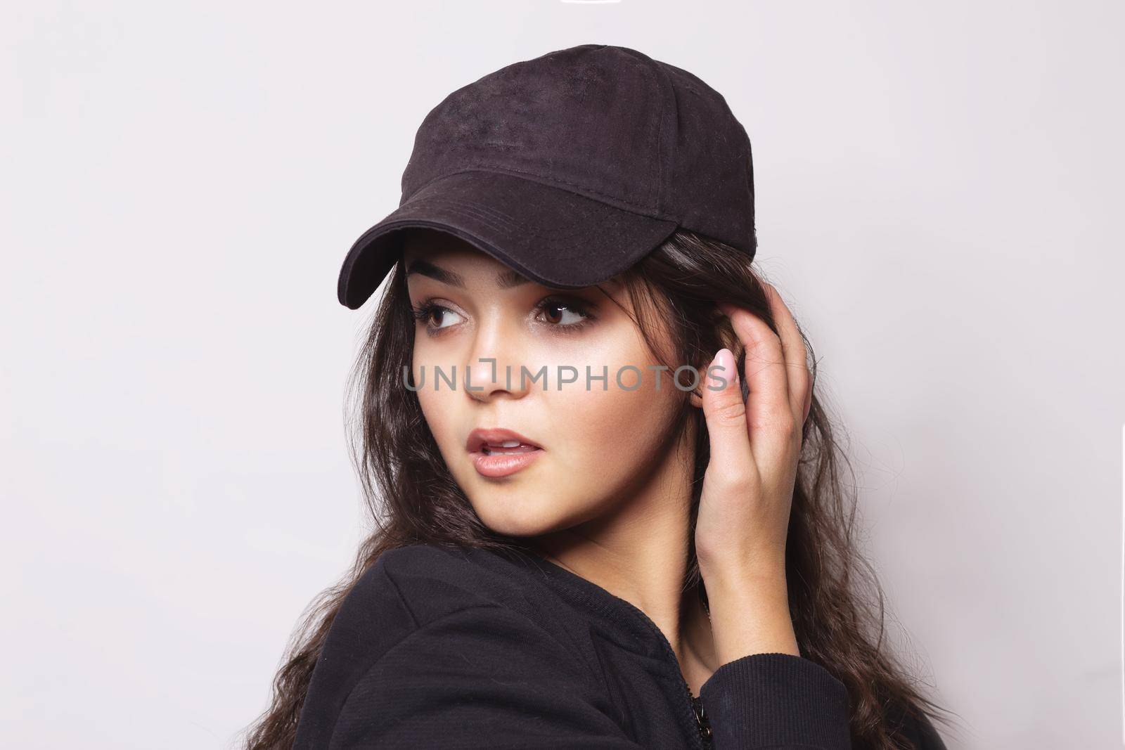 Very attractive young woman in a cap posing expressing surprise in the studio on a gray background