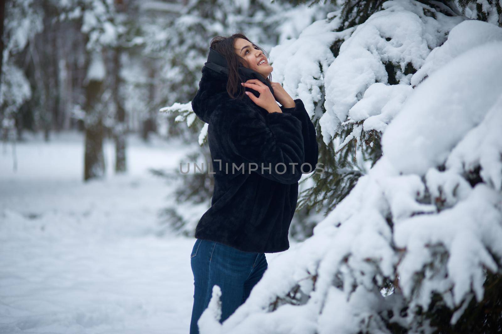 Young woman rejoices in the first snow in the forest