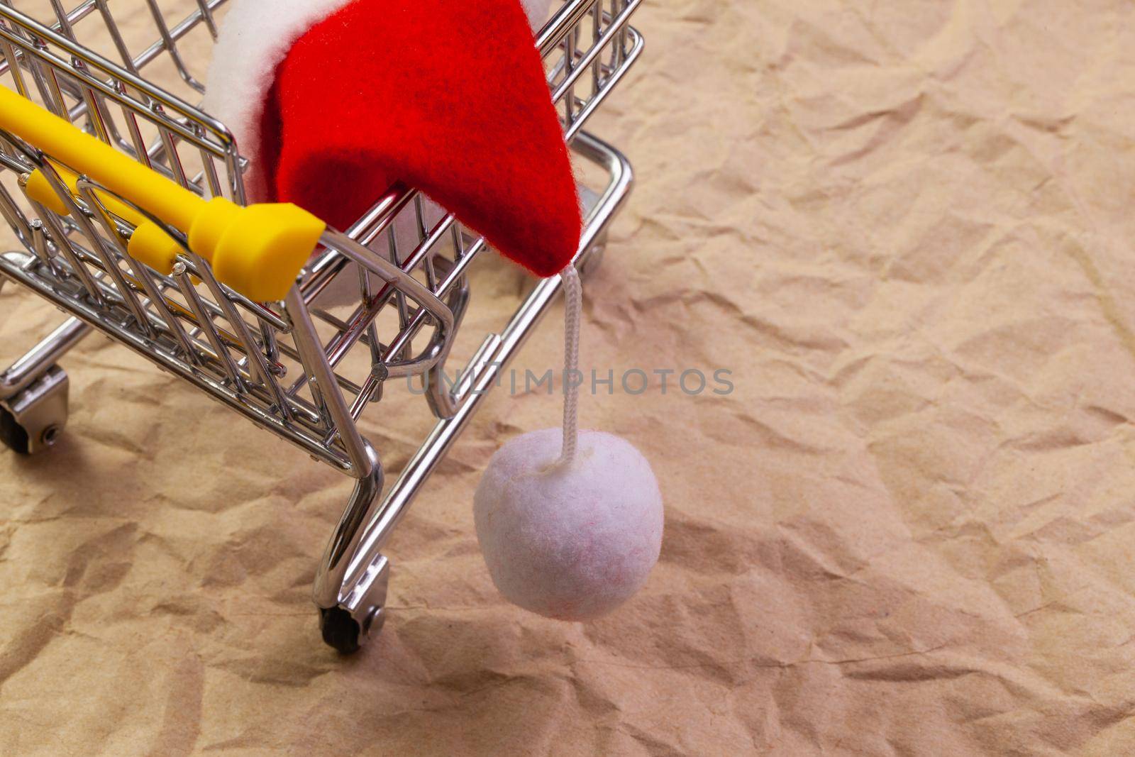 Shopping trolley and red Santa Claus cap. Winter holidays.  by CaptureLight