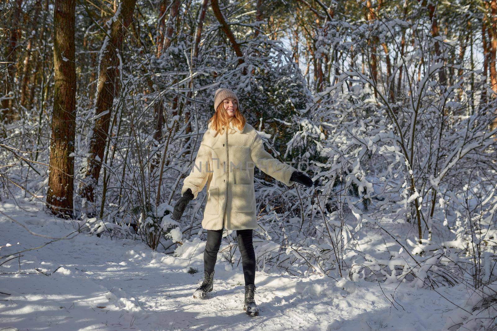 Happy woman walking in snow outdoors nature. Joyful young person relaxing on an outdoor walk activity in snowy forest landscape