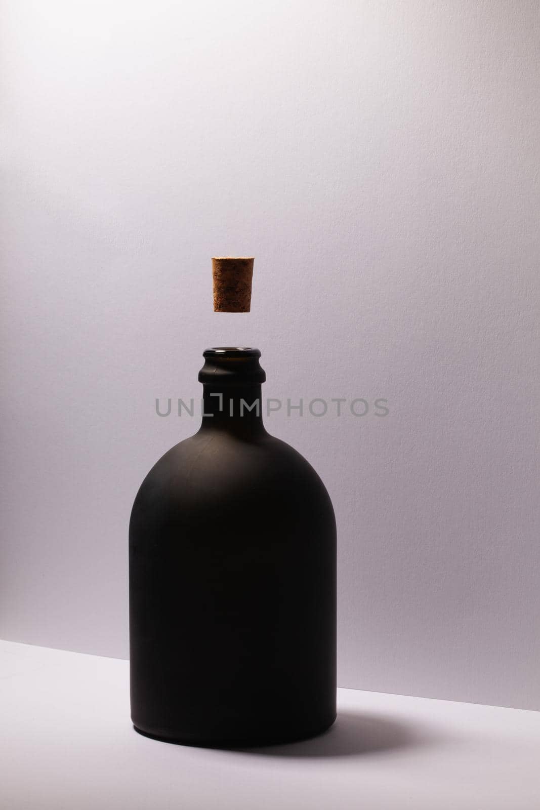 Luxury Black Glass of Rum on the white background. Levitating cork stopper.