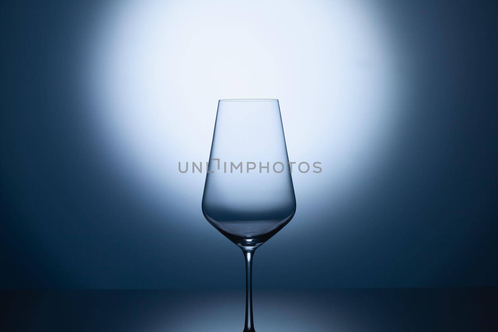 Empty wine glass on a blue clean gradient background. Empty drinking transparent wine glass