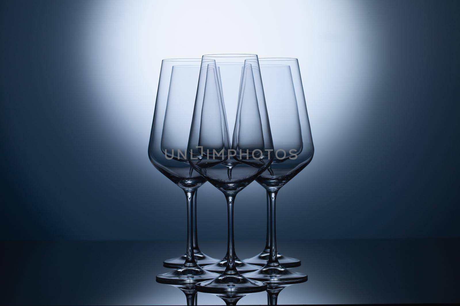 Empty wine glasses on a blue clean gradient background. Empty drinking transparent wine glasses