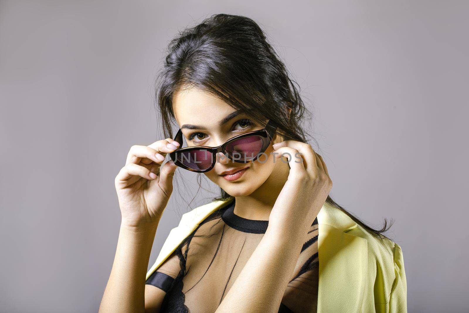 Portrait of a happy beautiful young woman in stylish sunglasses. The girl adjusts glasses
