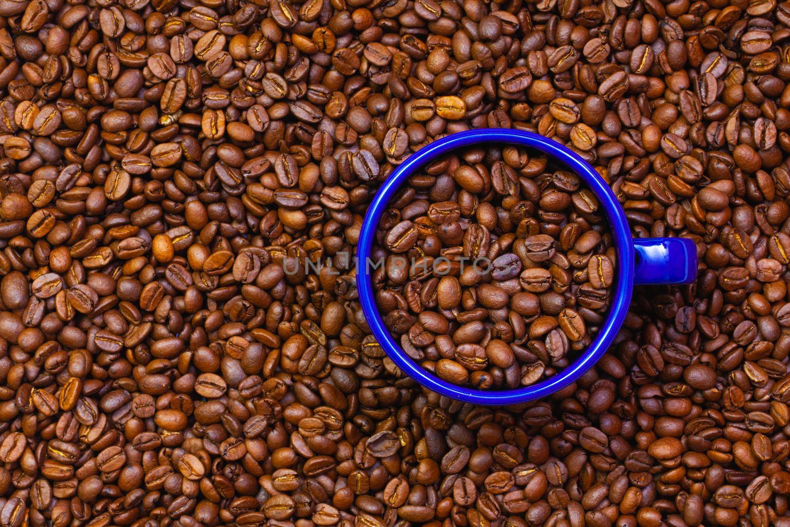 Blue tin mug full of coffee beans.  by CaptureLight