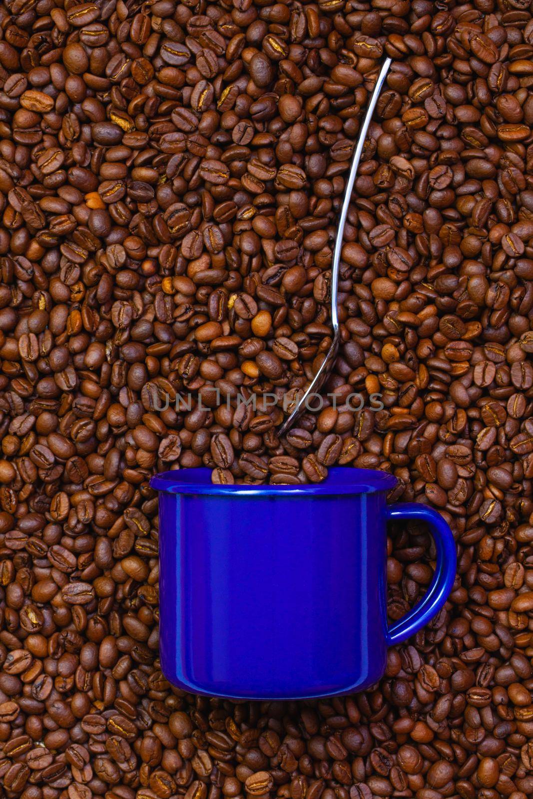 Blue cup of coffee on a table full of coffee beans.  Coffee design.