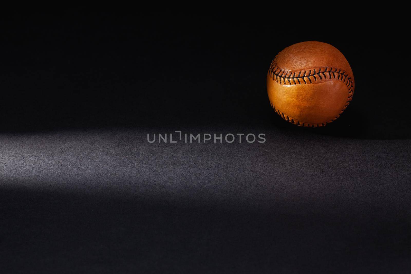Brown baseball ball ion the black background.  by CaptureLight
