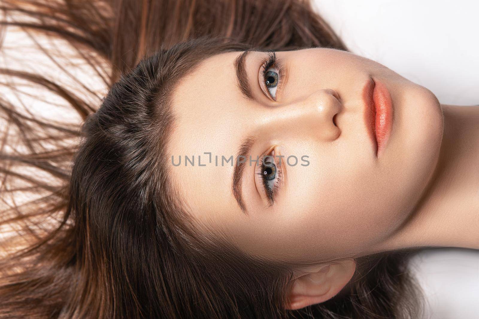 Portrait of a young woman with her hair spread while lying in a studio