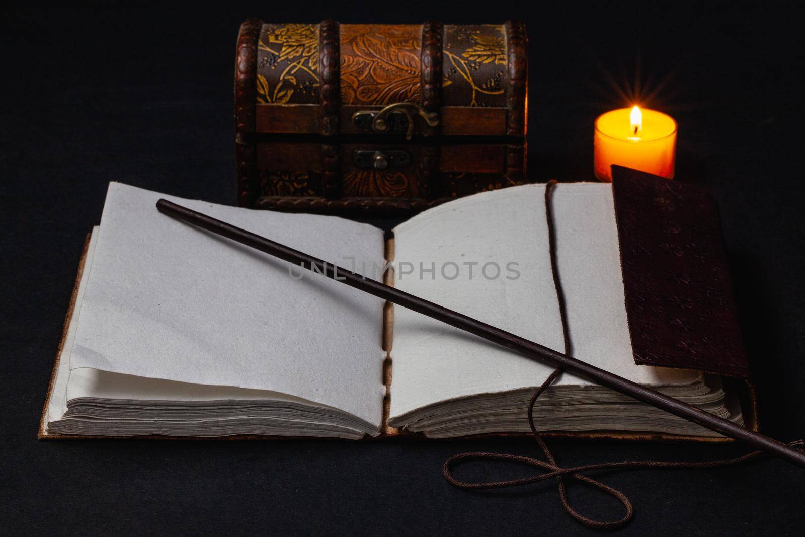 Image of open magic book and wand on the table in the dark room.