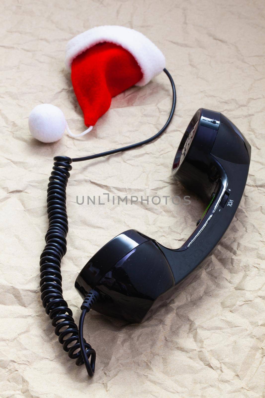 Old handset and Santa Claus cap on crumpled paper.  Winter holidays. Merry christmas and happy new year concept.