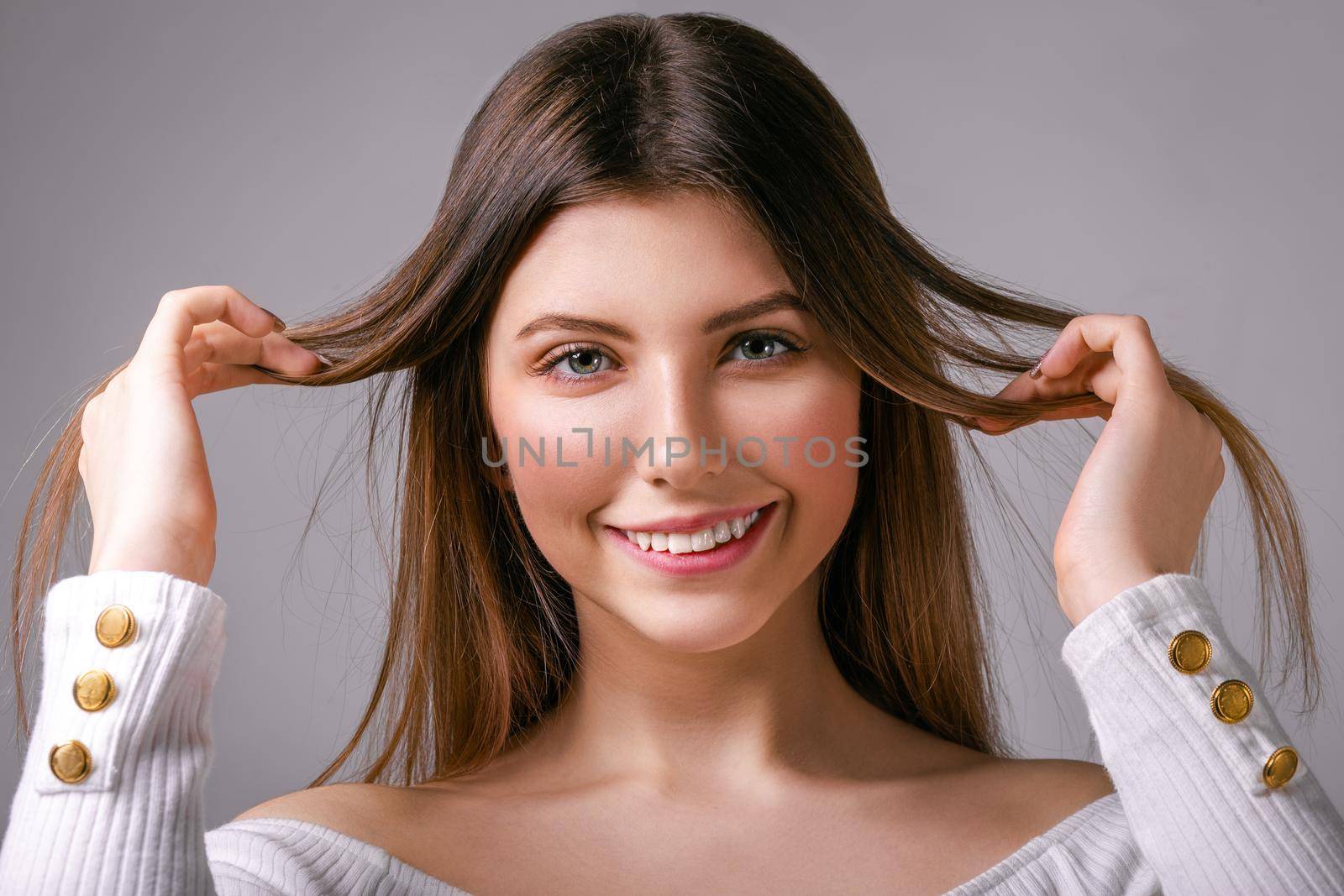 Delighted young girl with loose hair stands on a gray background looking by AliaksandrFilimonau