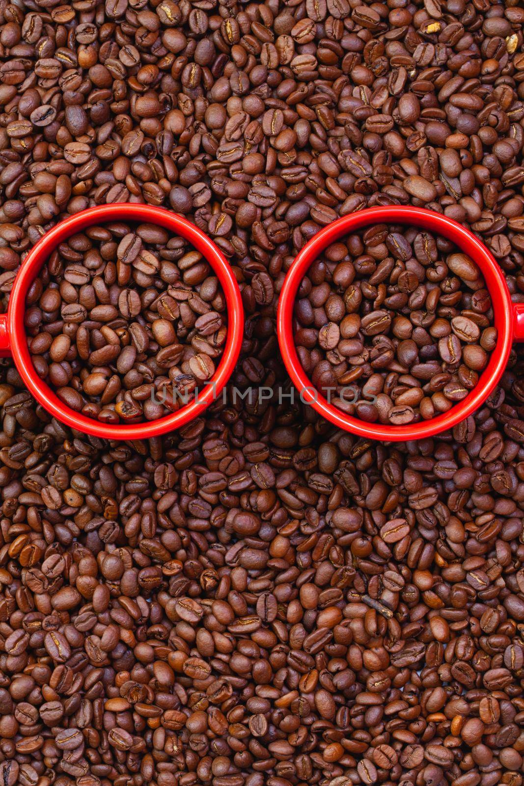Two red cups full of coffee beans. Fair Trade. Commodity trade. Fresh coffee beans.