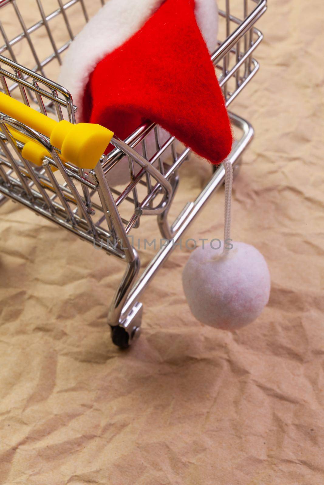 Shopping trolley and red Santa Claus cap. Winter holidays.  by CaptureLight