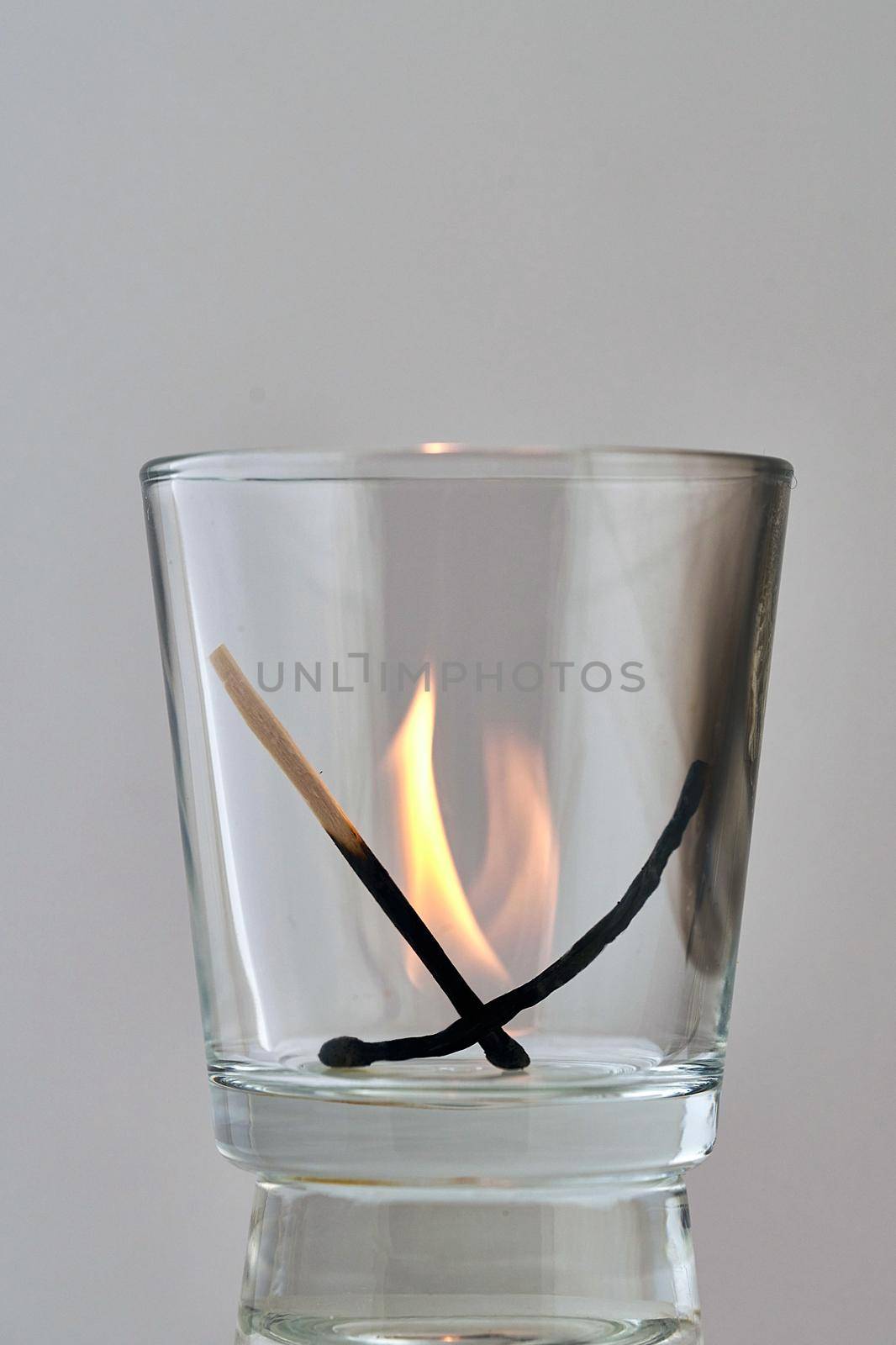 Two charred matches burn out in a transparent glass by vizland