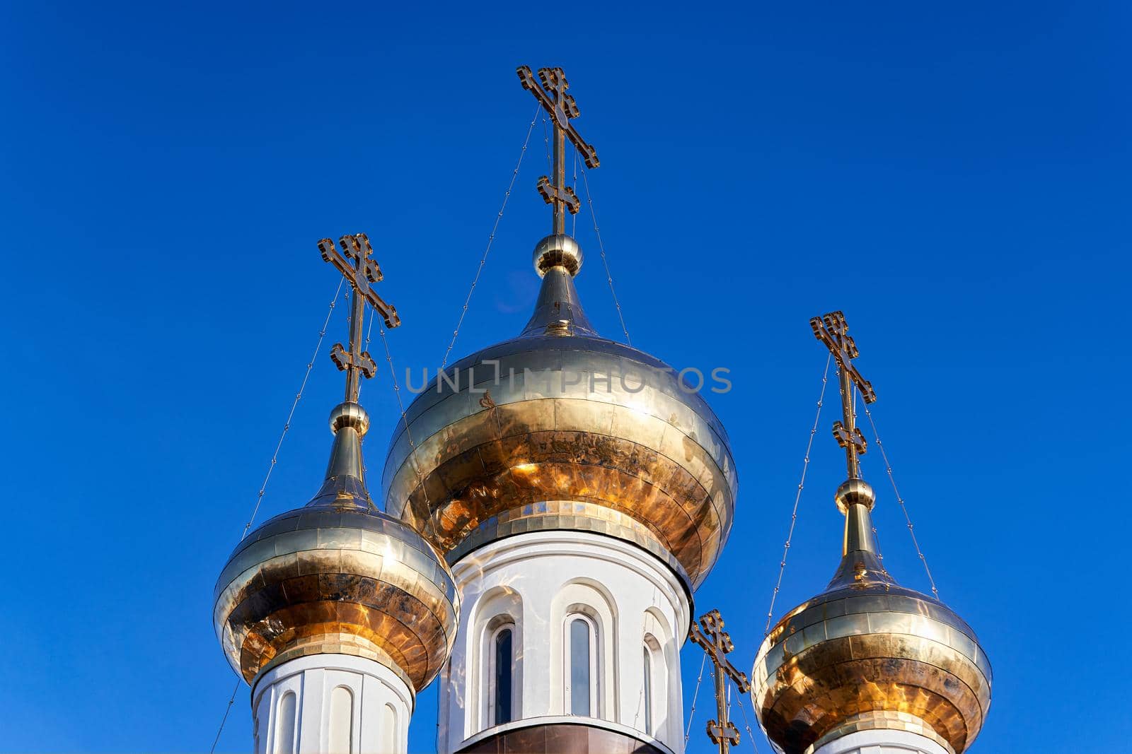 Church golden domes with Orthodox crosses against the blue sky. Close up