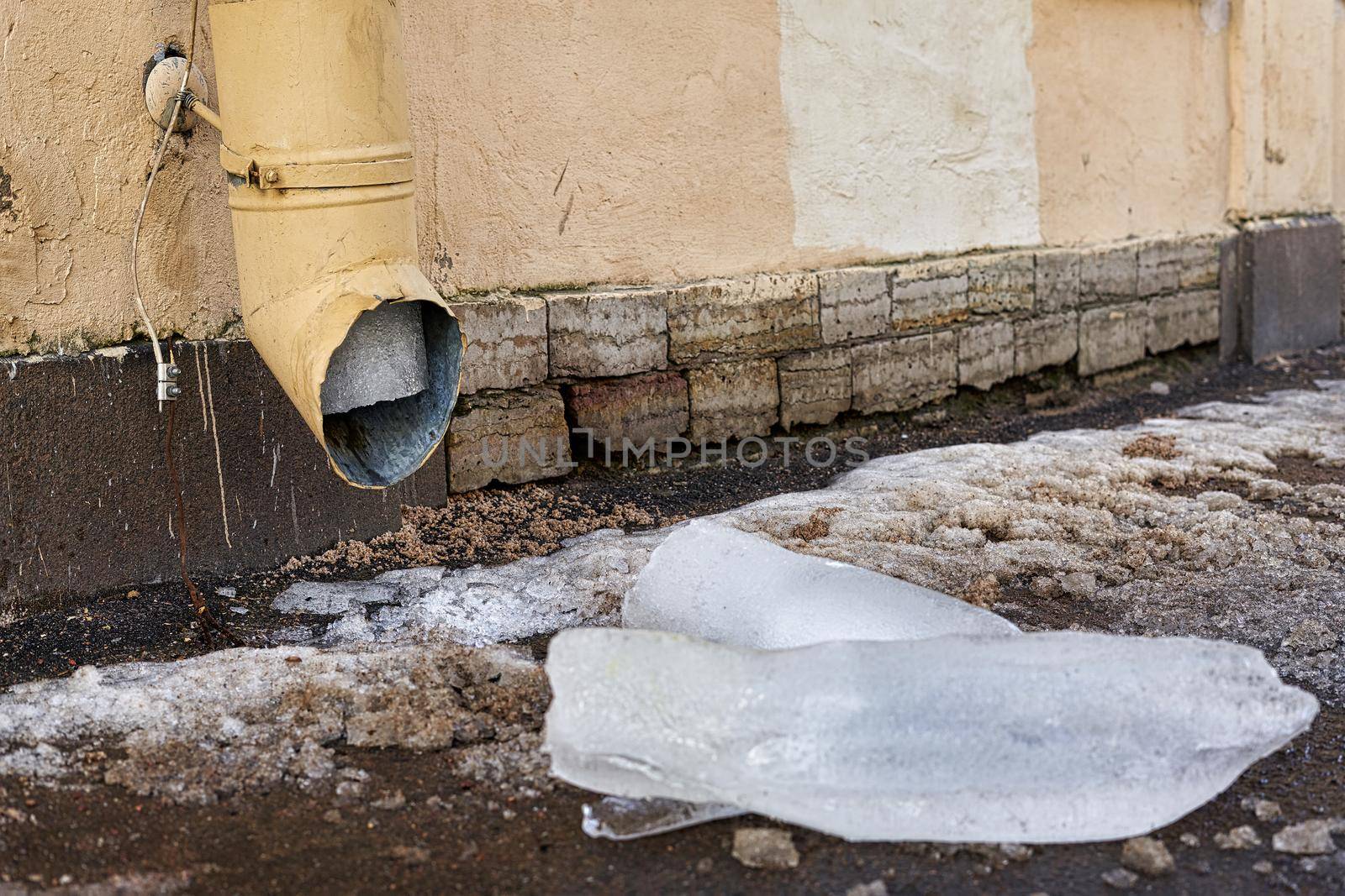 A large piece of ice dropped from the drainpipe lies on the street. Close up