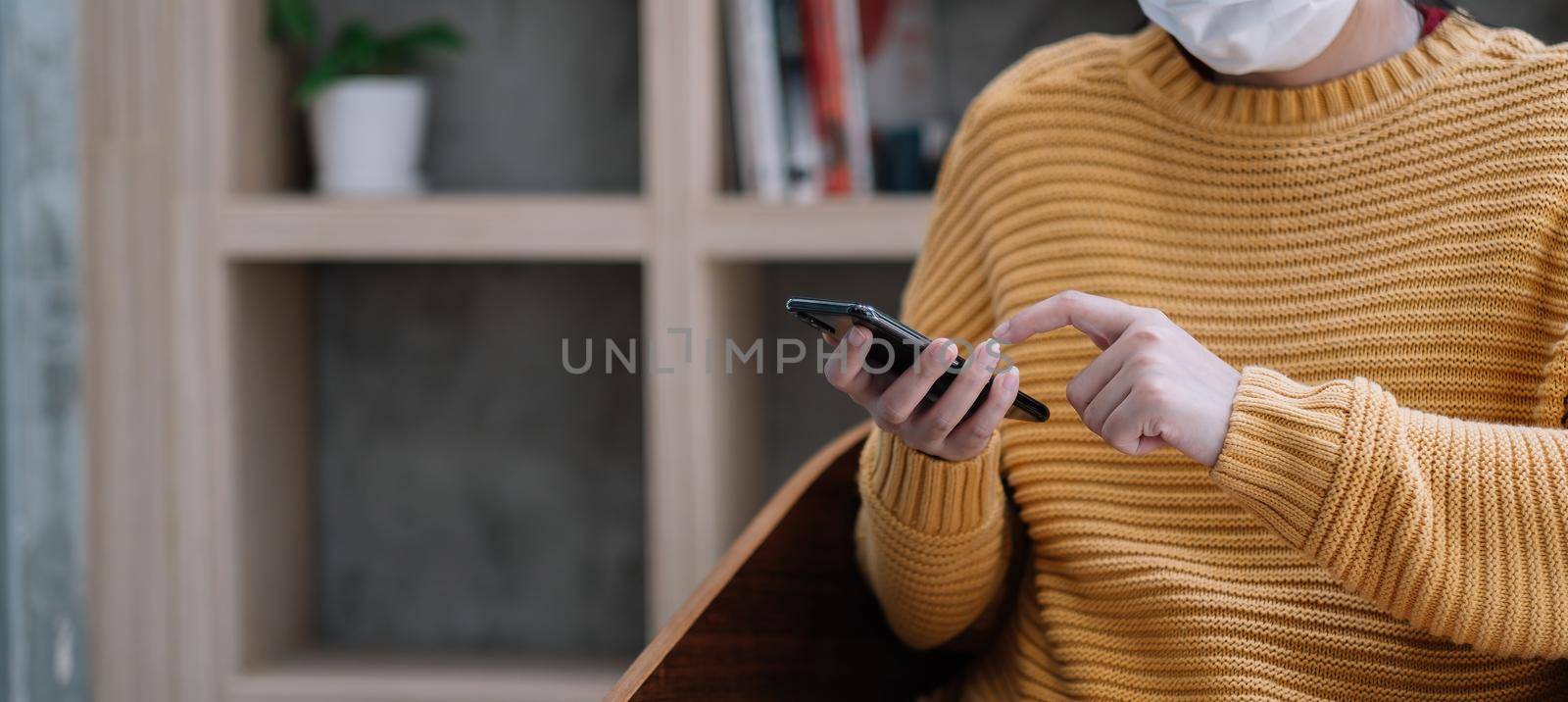 Woman in medical mask using mobile phone. Isolation at home.