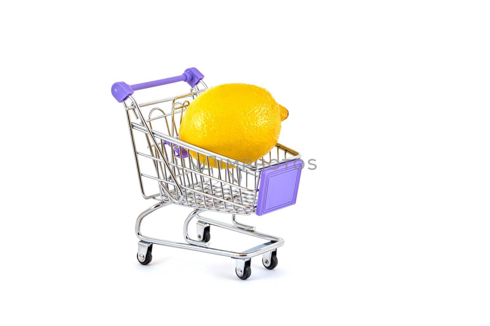 A ripe yellow lemon lies in a small supermarket trolley on a white background, close up