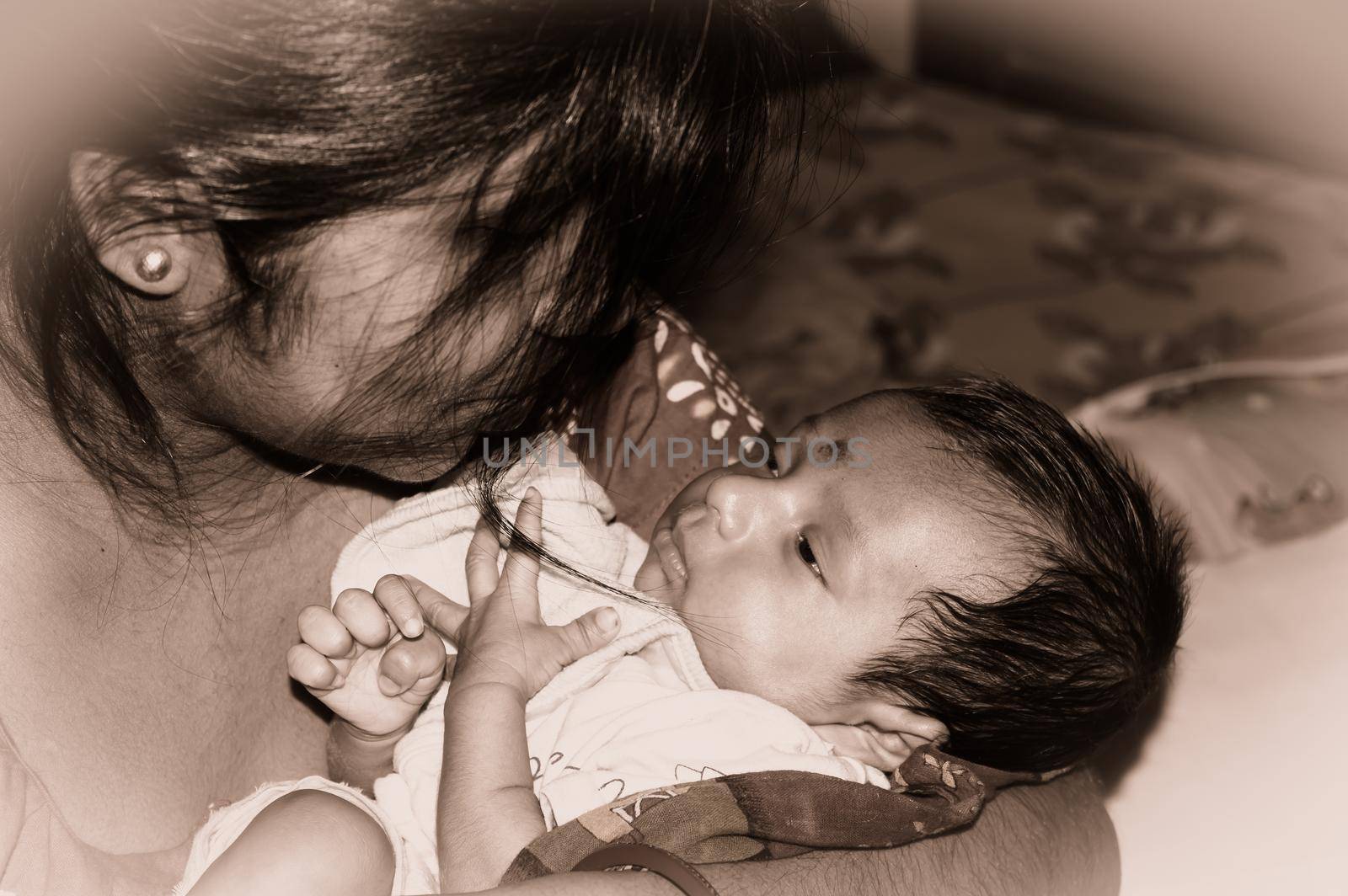 Adorable Mom and lulling newborn baby son. Loving portrait of happy mum hugging infant child on hands. Young Mother and little baby emotional attachment on Maternity Leave at home. Good morning. by sudiptabhowmick