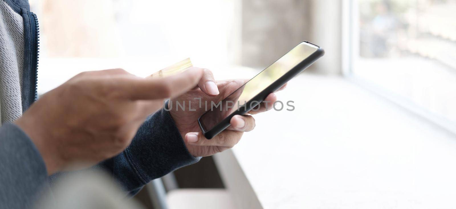 Online payment,Man's hands holding a credit card and using smart phone for online shopping.