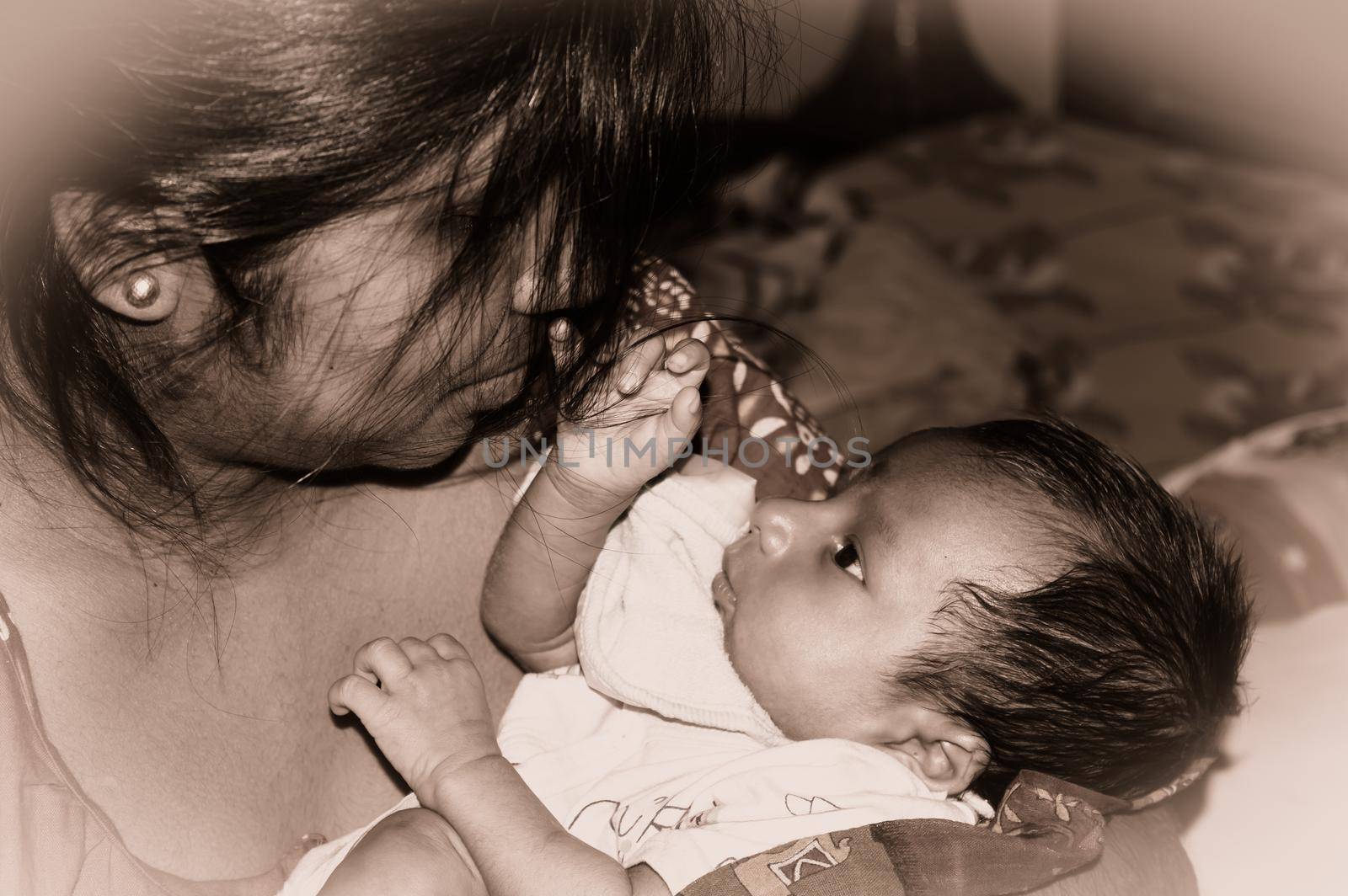 Adorable Mom and lulling newborn baby son. Loving portrait of happy mum hugging infant child on hands. Young Mother and little baby emotional attachment on Maternity Leave at home. Good morning.