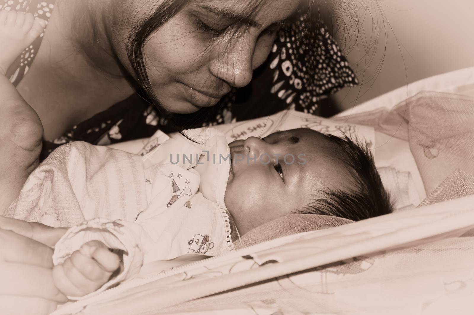 Cute newborn baby boy looks at his mother in her mother lap playing on bed. Close up. One month old Sweet little infant toddler. Indian ethnicity. Front view. Happy mother’s day background image.
