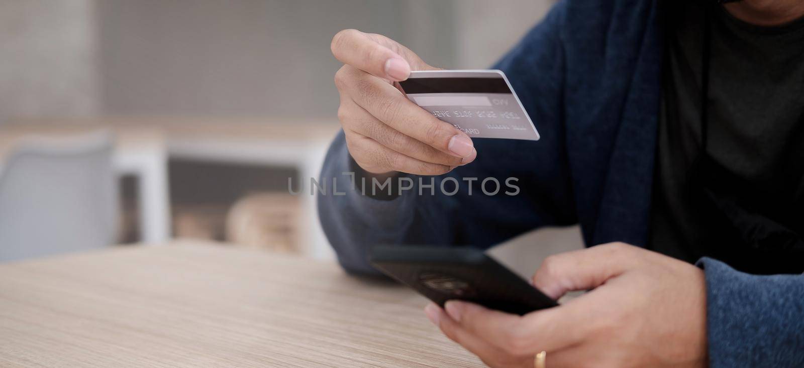 Online payment,Man's hands holding a credit card and using smart phone for online shopping by wichayada