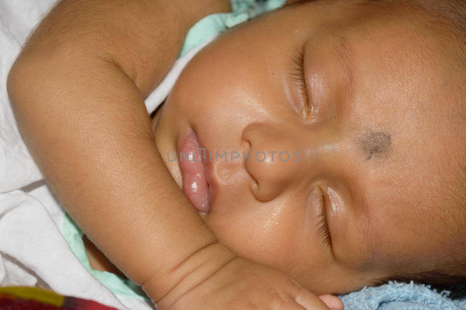 Close up face of a cute sleeping newborn baby. Closeup portrait of a Sweet just born infant boy captured in sleepy mood drowsy eyes. Hand on Chin. Front view. Child care kid background image. by sudiptabhowmick